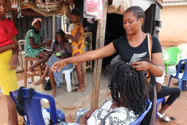 : Giwa Juliet and her apprentice making hair for a client in her shop